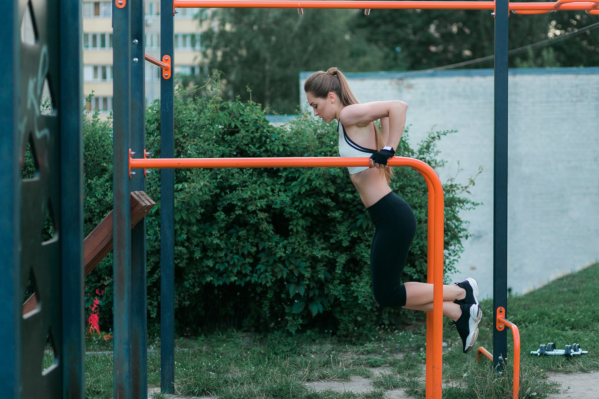 strong-physically-fit-young-woman-doing-triceps-dips-parallel-bars-park